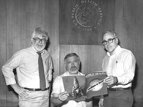 שלושה ממנהלי התוכנית העולמית להכחדת האבעבועות השחורות בעת ההכרזה על הצלחת המבצע. מימין לשמאל: ויליאם פויג (Foege), מייקל ליין (Lane) ודונלד מילר (Millar) | צילום: CDC, נחלת הכלל