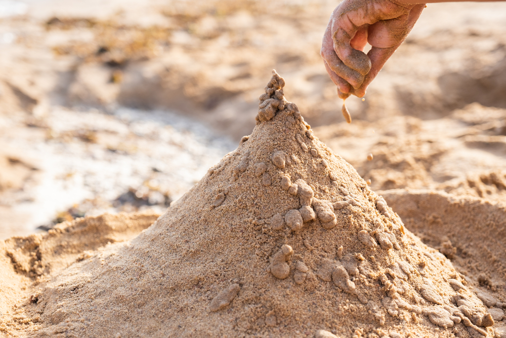 אם נוסיף חול לתלולית הגובה יגדל מהר יותר מהבסיס, והחול החדש יתחיל להתגלגל במורד, בגלל זווית החיכוך. תלולית חול על חוף הים | צילום: Rudenko Alla, Shutterstock