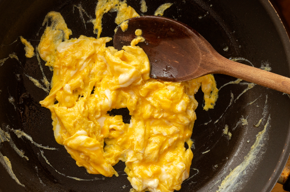 מומלץ לערבב משולי המחבת כלפי המרכז. טיגון ביצה מקושקשת | צילום: youngoggo, Shutterstock