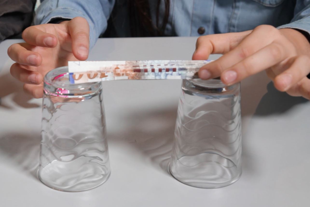 גשר משטר נייר – הנייר מקופל למקטעים כמעט מאונכים לקרקע | צילום מסך מתוך סרטון מדע בבית