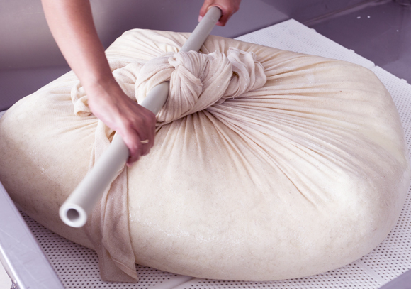 ככל שמנקזים יותר נוזלים ומפעילים לחץ ממושך יותר, הגבינה תהיה קשה יותר. ייצור מסורתי | צילום: Shutterstock