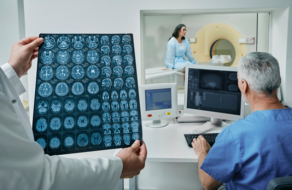 חוקר מסתכל על תמונות MRI של מטופלת | Peakstock, Science Photo Library