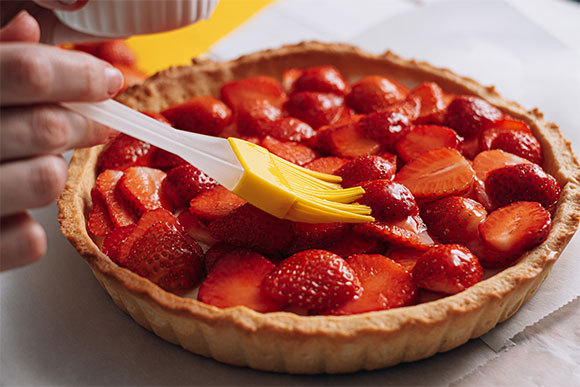 אישה מורחת מי סוכר על פאי תותים | Shutterstock, Mikhaylovskiy