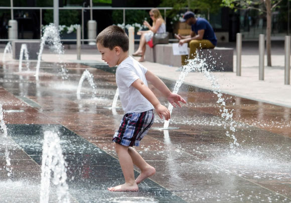 ילד משחק במזרקות ברחוב | Susan B Sheldon, Shutterstock