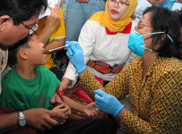 בדיקה לילד באינדונזיה במהלך התפרצות שפעת העופות | צילום: Toto Santiko Budi, Shutterstock