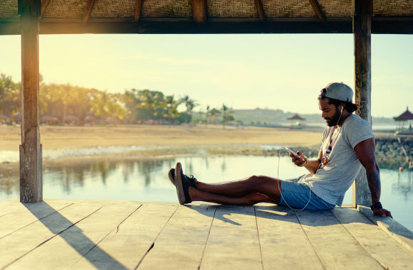 אדם נרגע בטבע ומקשיב למוזיקה באוזניות | Shutterstock, kudla
