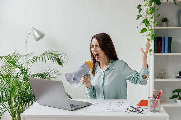 אשת מקצוע מחווה בידיה ומגבירה את קולה בשיחת וידאו | ViDI Studio, Shutterstock