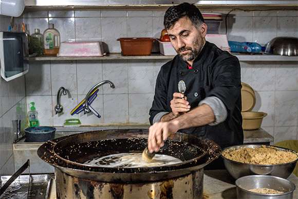 **תמונה של איש מבשל פלאפל** אף שכיום הפלאפל הוא לגמרי ישראלי, לא לגמרי ברור מאין הוא הגיע במקור ומתי טוגן כדור הפלאפל הראשון. | צילום Fotokon Shutterstock