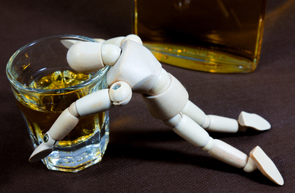 בובת עץ מעל כוס ויסקי | Shutterstock