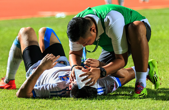 המחקרים אינם חד-משמעיים לגבי נזק בלתי הפיך. כדורגלן שנפגע בראשו מטופל על המגרש | צילום: Shutterstock