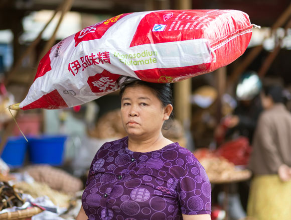 אישה במיאנמר נושאת על ראשה שק גדול של מונוסודיום גלוטמט | צילום: Shutterstock
