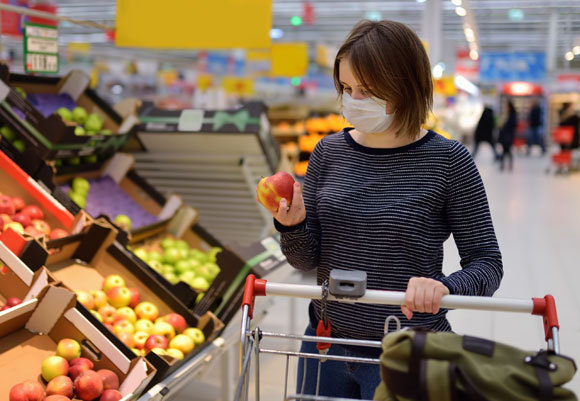 את הפירות והירקות עדיף לקרצף במים זורמים. אישה עם מסכת מגן בקניות במרכול | צילום: Maria Sbytova, Shutterstock