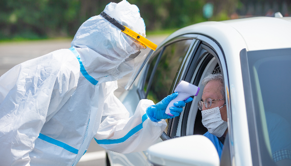 רופאה בבגדי מגן מודדת חום לחשוד בקורונה | צילום: aslysun, Shutterstock
