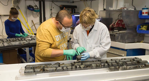 אדג'קום (מימין) בוחנת דגימות סלעים שנאספו בקידוחים | צילום: Jason Sylvan, TAMU