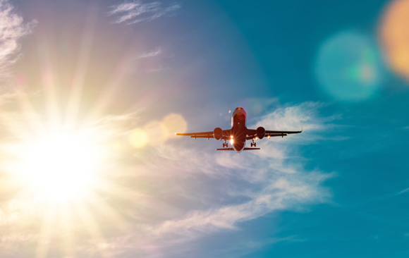 Ein Flugzeug am Himmel vor dem Hintergrund der Sonne | Shutterstock, bez_bretelky