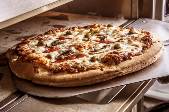 Eine Pizza wird in den Ofen geschoben