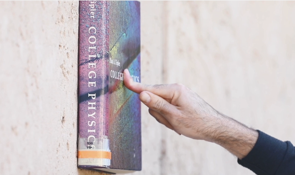 ספר מוצמד לקיר באמצעות אצבע | צילום: ליאורה זייתון