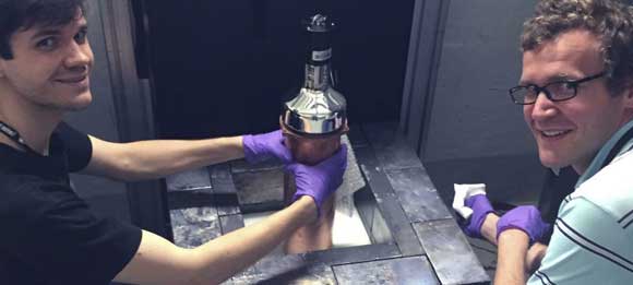 שניים מהחוקרים עם גלאי הניטרינו וחלק ממעטפת ההגנה שנועדה לסנן החוצה חלקיקים אחרים | צילום: חואן קולר, אונ' שיקגו