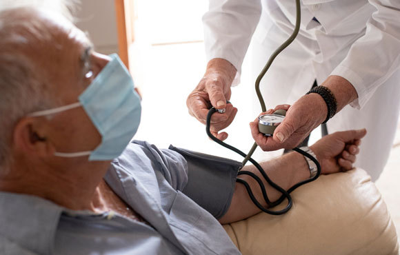 רופא מודד לחץ דם לחולה במסכה | צילום: Alessandro Pintus, Shutterstock
