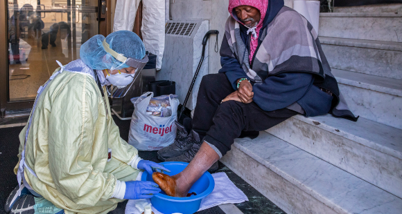 רופאה בדטרויט מטפלת בכף הרגל של חסר-בית חולה סוכרת | צילום: JIM WEST / SCIENCE PHOTO LIBRARY