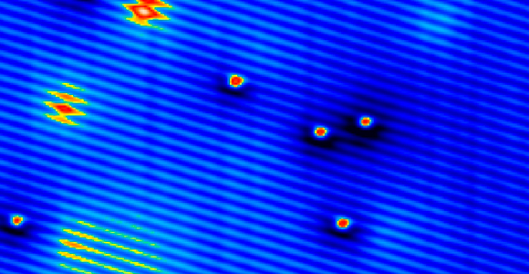 צילום (צבוע) במיקרוסקופ אלקטרונים המראה את הספינים של אטומי מנגן כענן אדום-צהוב | מקור: Science Photo Library