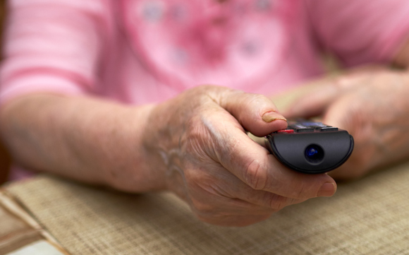 אישה מבוגרת מחזיקה בשלט טלוויזיה | Shutterstock