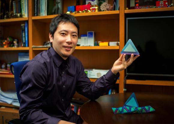 סוג חדש של גביש. ראש צוות המחקר, אוּ צֶ'ן, עם דגם של פירמידה המרכיבה את הגביש | צילום: אוניברסיטת בראון