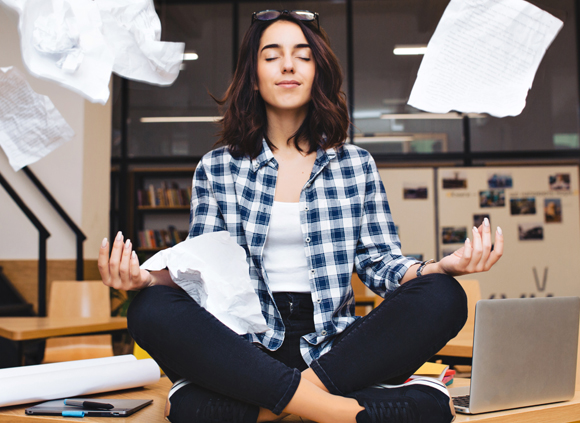 אישה מבצעת מדיטציה על שולחן העבודה שלה | Shutterstock