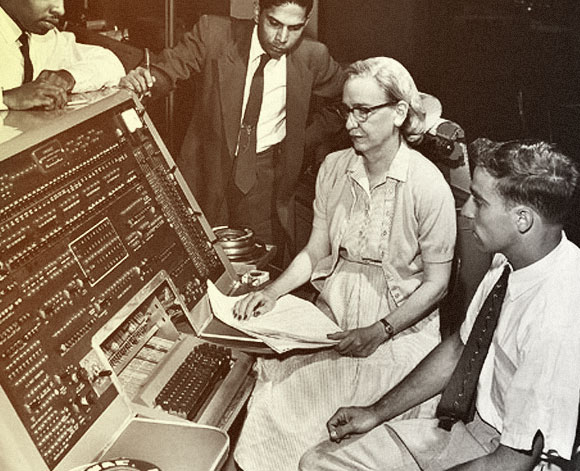 מהדורה ראשונה. הופר וצוותה בוחנים את פעולת המהדר במחשב UNIVAC מוקדם | מקור: ויקיפדיה